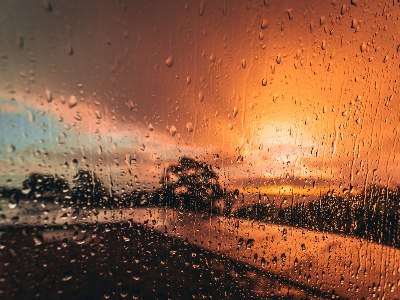 雨粒のついた窓越しに見える夕焼けの景色